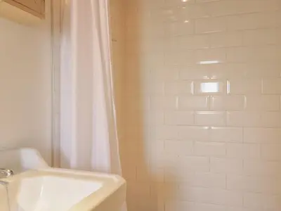 a bathroom with a white shower curtain and a sink at Sweetpea Cottage in Wiston