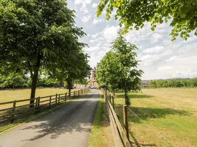 a road through a field with trees and a fence at The Mews Flat in Dalswinton