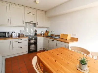 a kitchen with white cabinets and a wooden table at Mellfell Cottage in Watermillock