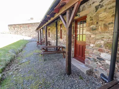 a group of benches sitting outside of a stone building at Mellfell Cottage in Watermillock