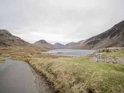 a road next to a lake in the mountains at Stable End Cottage in Nether Wasdale