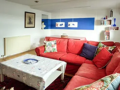 a living room with a red couch and a table at Fish House in Kirkcudbright