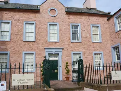 a brick house with a green door and a fence at Fish House in Kirkcudbright