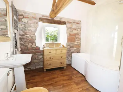 a bathroom with a white tub and a sink and a bath tub at Faraway Cottage in Kirklinton