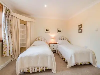 a bedroom with two beds and a table with a lamp at Little Laight in Cairnryan
