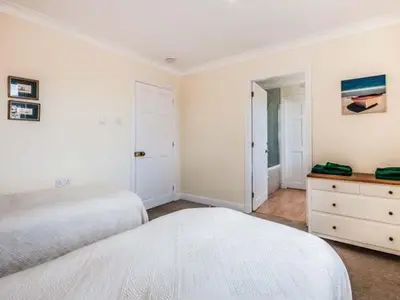 a white bedroom with a large bed and a dresser at Little Laight in Cairnryan