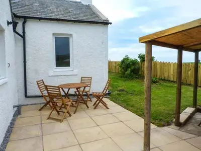 a patio with a table and chairs in a yard at Simmer Dim in Kirkbean