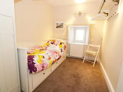 a small bedroom with a bed and a chair at Simmer Dim in Kirkbean