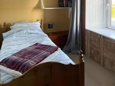 a bed with a blanket on it in a bedroom at The Pink House in Isle of Whithorn
