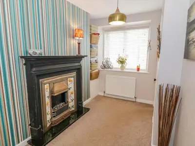 a living room with a fireplace and a striped wall at Nathaniel's Cottage in Kirkcudbright
