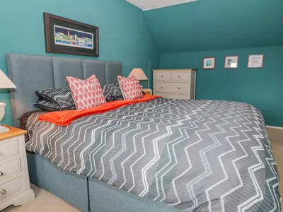 a bedroom with a large bed with blue walls at Nathaniel's Cottage in Kirkcudbright