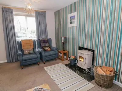 a living room with two chairs and a stove at Nathaniel's Cottage in Kirkcudbright