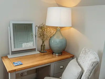a lamp on a table with a mirror and a chair at Corsewall Castle Farm Lodges in Kirkcolm