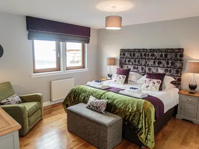 a bedroom with a large bed and a chair at Corsewall Castle Farm Lodges in Kirkcolm