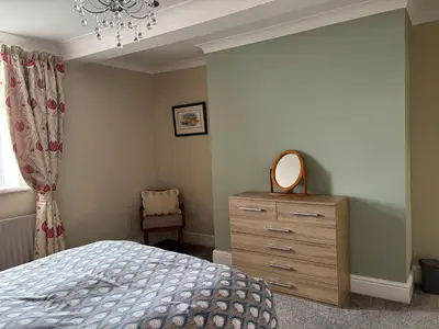 a bedroom with a bed and a dresser with a mirror at Greenmantle in Skinburness