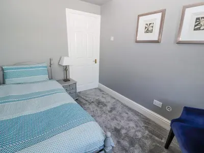 a bedroom with a bed and a blue chair at Greenmantle in Skinburness