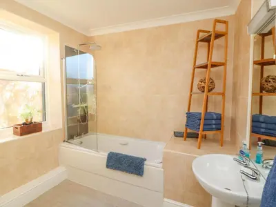 a bathroom with a tub and a sink and a toilet at Greenmantle in Skinburness