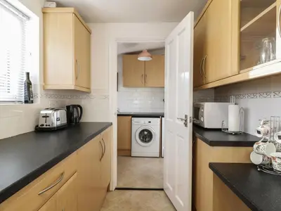 a kitchen with wooden cabinets and a washer and dryer at 1 Rubby Banks Road in Cockermouth