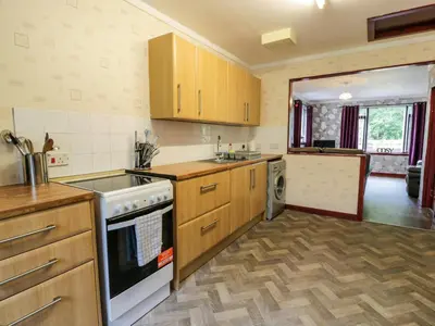 a kitchen with wooden cabinets and a stove top oven at Torkeld Holiday Cottage in Garlieston