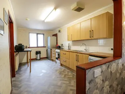 a kitchen with wooden cabinets and a sink and a refrigerator at Torkeld Holiday Cottage in Garlieston