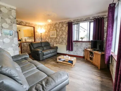 a living room with a couch and a television at Torkeld Holiday Cottage in Garlieston