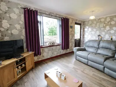 a living room with a couch and a television at Torkeld Holiday Cottage in Garlieston