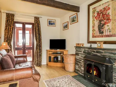 a living room with a fireplace and a tv at Barn Roost in Uldale