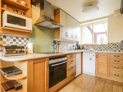 a kitchen with wooden cabinets and a stove top oven at Barn Roost in Uldale