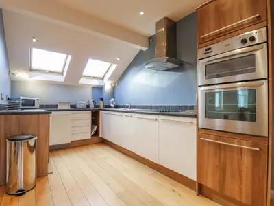 a kitchen with white cabinets and stainless steel appliances at Wrenville in Keswick
