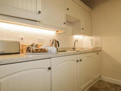 a kitchen with white cabinets and a sink at Ale Cottage in Ireby