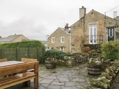 a garden in front of a stone house at Ale Cottage in Ireby
