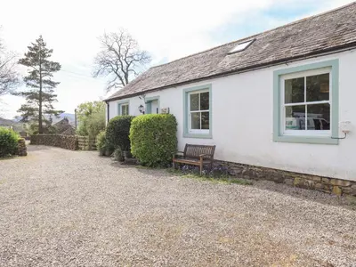 a white house with a bench in front of it at Mell View Cottage in Watermillock