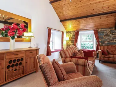 a living room with chairs and a vase of red roses at Coombe Cottage in Borrowdale Valley