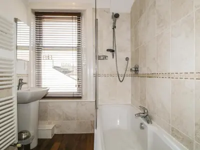 a bathroom with a shower and a tub and a sink at Helvellyn in Keswick