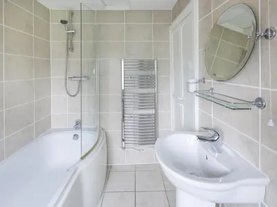 a bathroom with a tub and a sink and a mirror at Ellwood House in Caldbeck