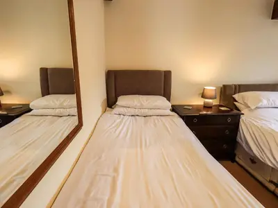 a room with two beds and a mirror at Scales Cottage in Lorton