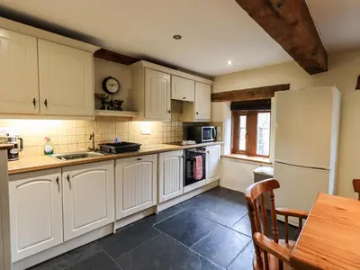a kitchen with white cabinets and a table and a refrigerator at Scales Cottage in Lorton
