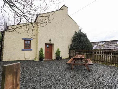 a wooden picnic table in front of a building at Scales Cottage in Lorton