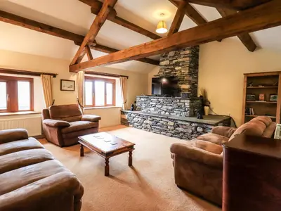a living room with couches and a stone fireplace at Scales Cottage in Lorton