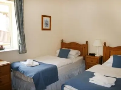 a bedroom with two beds with blue and white sheets at Whitbarrow Holiday Village Troutbeck 5 in Penruddock