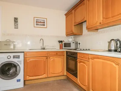 a kitchen with wooden cabinets and a washer and dryer at Castlerigg in Keswick