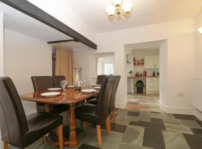 a dining room with a wooden table and leather chairs at Fountain Cottage in Keswick