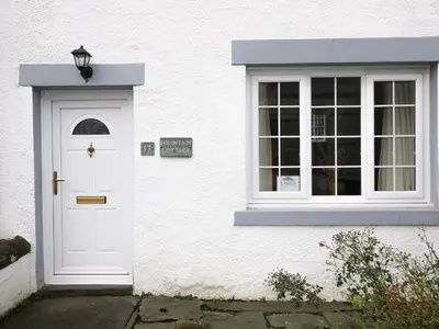 a white house with a white door and a window at Fountain Cottage in Keswick