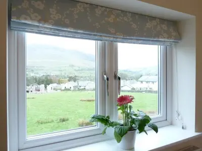 a window with a flower in a vase on a window sill at Eribel Cottage in Threlkeld