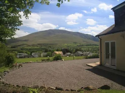 a driveway leading to a house with a mountain in the background at Eribel Cottage in Threlkeld