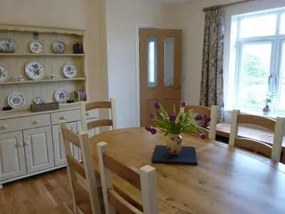 a dining room table with a vase of flowers on it at Eribel Cottage in Threlkeld