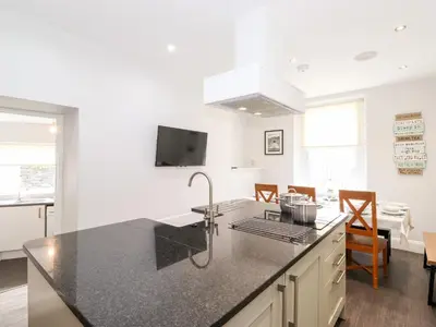 a kitchen with a counter top and a living room at Latrigg House in Keswick