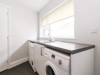 a laundry room with a sink and a washing machine at Latrigg House in Keswick