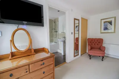 a living room with a tv and a dresser with a mirror at Derwentwater Apartment in Keswick