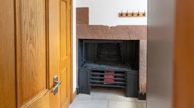 a fireplace in a room next to a door at Heads Nook Hall Cottage in Carlisle